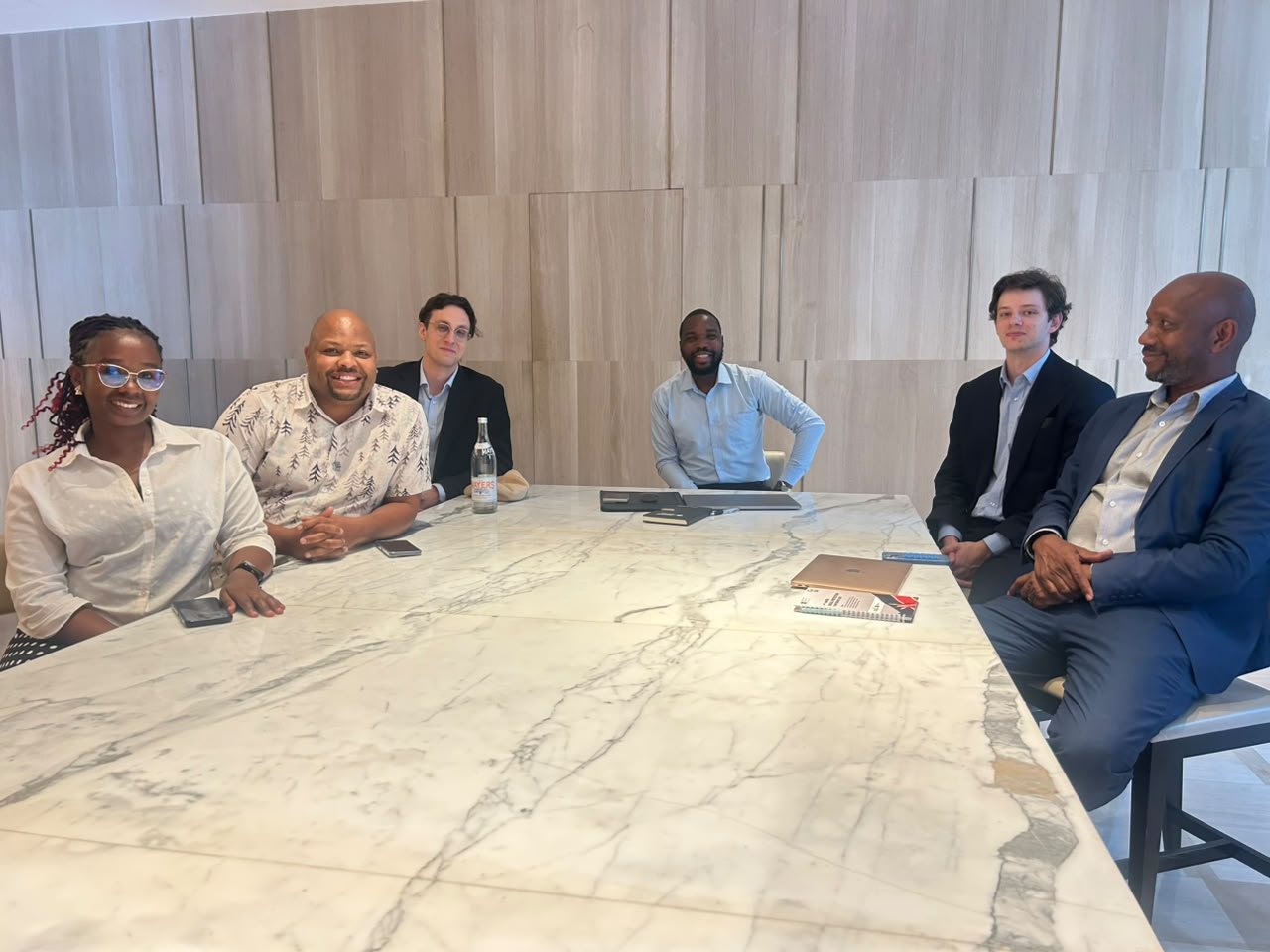 Six people seated around a marble table smiling at the camera